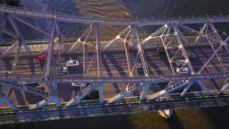 Tilting-down-aerial-slow-motion-view-of-a-metal-bridge-and-passing-cars