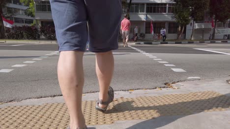 Lower-view-of-the-man-wearing-short-and-adventure-sport-sandal-while-walking-cross-the-street-in-singapore-area-in-slowmotion-view