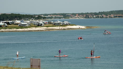 Stand-Up-Paddlers,-windsurfers,-pedal-boats-and-inflatable-boats-ride-on-the-sea-in-Premantura-Istria-Croatia