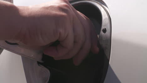 Close-up-of-a-woman's-hand-tightening-the-cap-on-the-gas-tank-of-a-white-vehicle