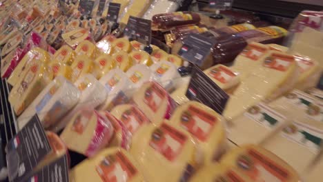 Panning-camera-over-the-cheese-shelf-stall-in-supermarket-with-many-kind-of-cheeses