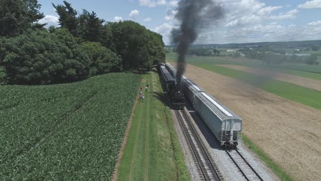 Aerial-View-of-Farmlands-and-Countryside-with-a-Vintage-Steam-Train-Puffing-up-to-Start-up-on-a-Sunny-Summer-Day