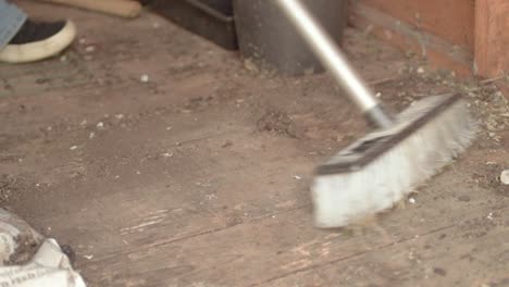 Homeowner-sweeping-dirt-and--dust-in-timber-shed