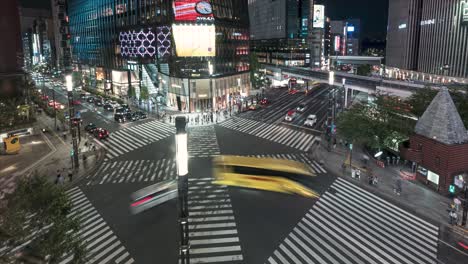 Sukiyabashi-Cruzando-Por-La-Noche-Con-Vehículos-Y-Personas-Cruzando-La-Calle-Por-La-Noche-En-Ginza,-Tokio,-Japón