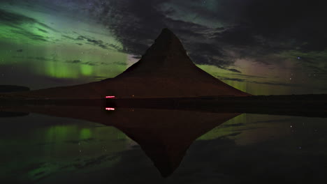 Iceland,-Kirkjufell:-Northern-Lights-Timelapse-with-Lake-Reflection-and-Cars-Passing-By