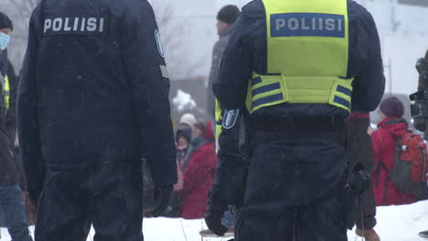 Shot-of-police-officers-standing-among-crowds-an-the-covid-19-demonstrations-in-Helsinki,-cold-snowy-day