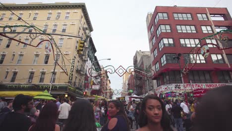 NYC:-Little-Italy-street-market-at-an-intersection,-in-the-middle-of-a-crowd-surrounded-by-food-stalls-and-games---Gimbal-push-forwards---New-York-City,-USA