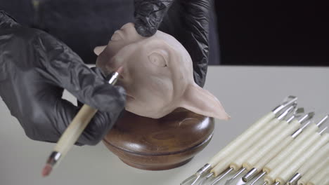 Artist-finishes-the-nose-of-a-plasticine-puppet-head-with-a-modeling-tool-4K