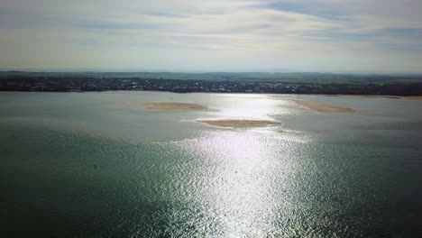 Aerial-footage-into-the-sun-of-Andersons-Inlet-flying-towards-the-town-of-Inverloch,-Victoria,-Australia