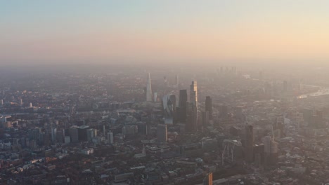 Slow-dolly-forward-drone-shot-towards-city-of-London-skyscrapers-at-sunset-golden-hour