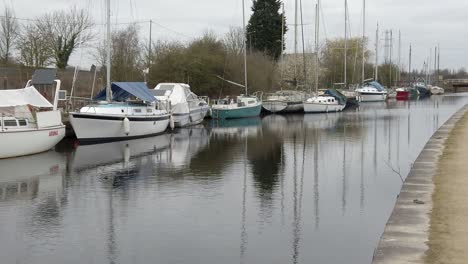 Small-sailboats-moored-on-quiet-rural-countryside-canal-marina