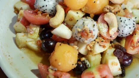 Nahaufnahmen-Von-Exotischen-Früchten-Im-Thailändischen-Stil,-Somtum-Mit-Süßem-Und-Salzigem-Dressing,-Darunter-Drachenfrucht,-Cashewnuss,-Traube,-Guave,-Melone-Und-Tomate