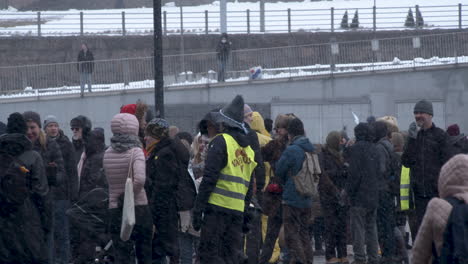 A-gathering-of-people-on-the-streets-of-Helsinki-some-in-high-visibility,-cold-snowy-day