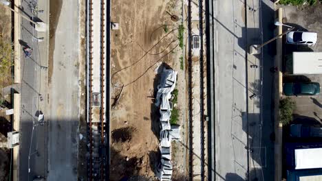 Aerial-slow-forward-drone-shot-of-an-empty-light-rail-on-construction-in-jaffa,-Israel,-surrounded-by-dirt-and-concrete