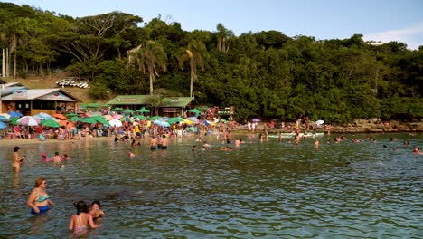 Schwenk-Links-Von-Menschen,-Die-Im-Meer-Schwimmen-Und-Sich-Am-Ufer-Des-Strandkomplexes-Praia-Da-Sepultura,-Brasilien,-Ausruhen