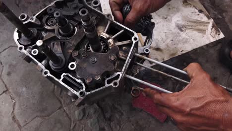 A-Vietnamese-mechanic-reconditioning-engine-parts-while-crouching-on-the-pavement