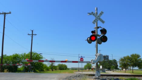 Rail-road-crossing-with-red-lights-flashing-and-barriers-going-up-after-train