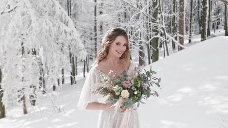 Beautiful-white-bride-poses-for-wedding-editorial-alone-in-snowy-winter-forest