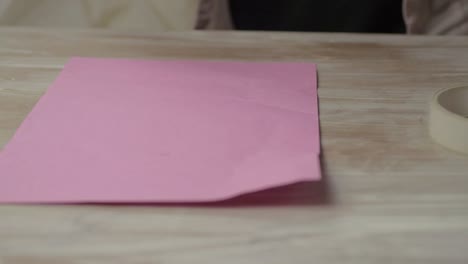 Woman-wrapping-gift-in-pink-paper