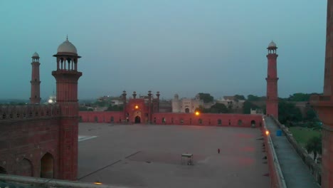 Pedestal-Aéreo-Detrás-De-La-Pared-De-Arenisca-Roja-De-La-Mezquita-Badshahi-En-Pakistán-Por-La-Noche