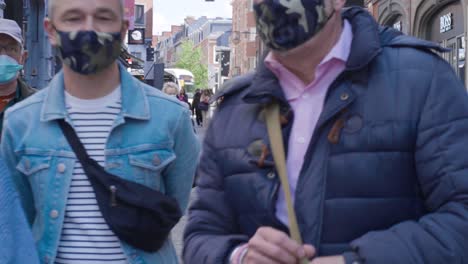 People-with-compulsory-face-masks-walking-straight-into-the-camera-in-the-city-centre-of-Leuven,-Belgium