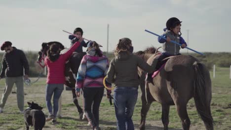 An-Einem-Sonnigen-Tag-In-Argentinien-Sitzen-Kinder-Mit-Hilfe-Von-Pferdetrainern-Auf-Der-Spitze-Des-Pferdes