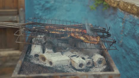 Stoking-charcoal-on-barbeque-before-placing-steak-on-grill-over-coals