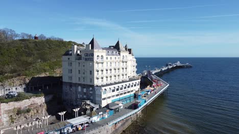 Aerial-view-of-The-Grand-hotel-landmark-Llandudno-seafront-seaside-Victorian-promenade-tourism-building-slow-push-in-right