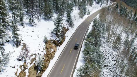 Jeep-wrangler-driving-through-snowy-mountains,-solo-adventure-road-trip