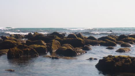 Felsen-Am-Strand-Mit-Kleinen-Wellen,-Die-Die-Küste-Erreichen