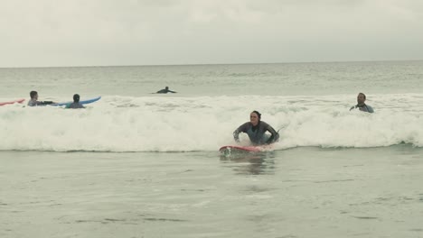 Mujer-Joven-Surfeando-En-Un-Día-Nublado-En-Portugal-Algarve-En-Una-Pequeña-Ola-En-El-Océano-Atlántico