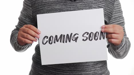 A-person-holding-a-sign-with-a-"coming-soon"-message