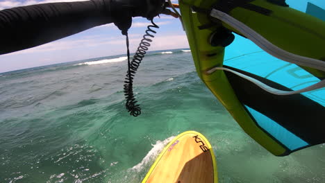Surfing-on-a-yellow-stand-up-paddleboard-with-a-green-and-blue-hydrofoil-above-the-ocean
