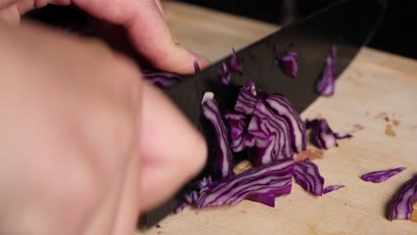 Close-up-cutting-red-cabbage-with-black-knife-on-wooden-chopping-board
