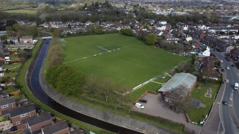 Aerial-drone-shot-over-rural-suburb-football-pitch-in-housing-estate,-England