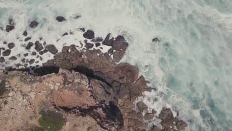 Aerial-top-down-flight-over-high-rock-cliffs-and-crashing-waves-of-Atlantic-Ocean-in-Portugal