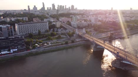 Drone-video-of-a-bridge-by-the-Vistula-River-at-sunset-in-Warsaw,-Poland