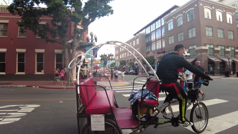 Man-Driving-Pedicab-Turn-And-Stop-In-The-Intersection-With-Stop-Light-Then-Use-A-Mobile-Phone-While-Waiting-At-San-Diego,-California