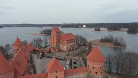 AERIAL:-Trakai-Island-Castle-and-Waving-Lithuania-Flag-with-Lake-and-Forest-in-the-Background