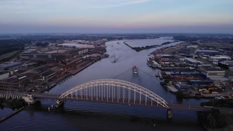 Sonnenuntergang-Luftaufnahme-Der-Brücke-über-Den-Noord-Mit-Frachtschiffen,-Die-An-Binnenhäfen-Vorbeifahren-Alblasserdam-Niederlande