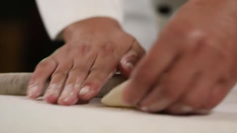 Hand-rolling-Chinese-dumplings-with-a-wooden-rolling-pin---side-view