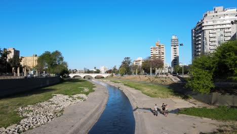 People-walking-on-riverbanks-of-Primero-River-in-Cordoba,-Argentina