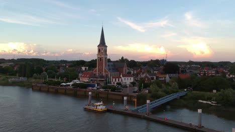Majestic-church-tower-and-small-pier-next-to-it-in-Belgium,-aerial-view