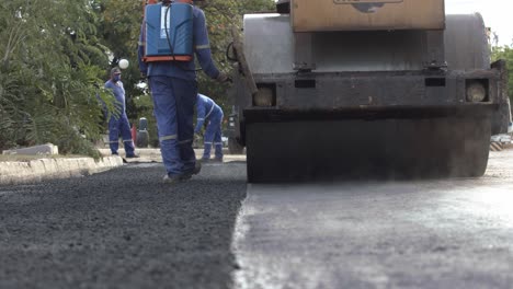 Workers-paving-a-rural-road-in-Corumba,-Brazil---hot-steam-rising-off-the-freshly-pressed-asphalt