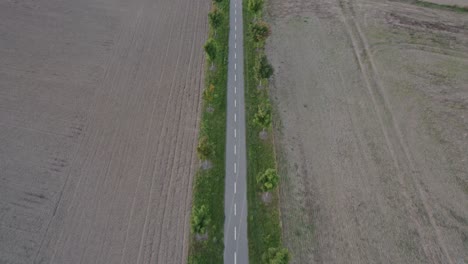 Flying-over-a-small-bike-path-in-the-middle-of-a-plowed-field