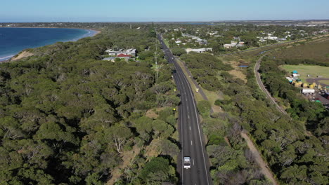 Low-aerial-follows-traffic-on-Bellarine-Hwy-in-Ocean-Grove,-Australia