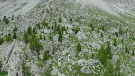Aerial-of-mountain-cable-car-climbing-between-rocky-slopes,-Dolomites
