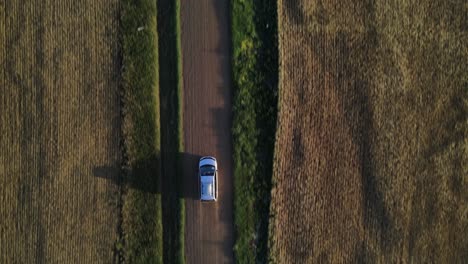Aerial-vertical-view-in-4k-of-parked-minivan-on-a-dusty-dirt-road-in-Canada's-countryside