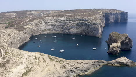 Yachten-Und-Boote,-Die-Unter-Den-Felsigen-Klippen-Der-Bucht-Von-Dwerja,-Malta,-Ankern