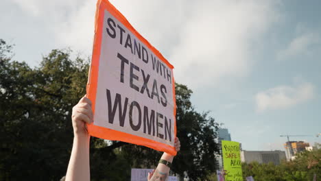 Protester-holds-STAND-WITH-TEXAS-WOMEN-sign-during-Women's-March-at-Texas-Capitol-in-Austin,-People-hold-signs-and-applaud-during-women's-rally,-4K